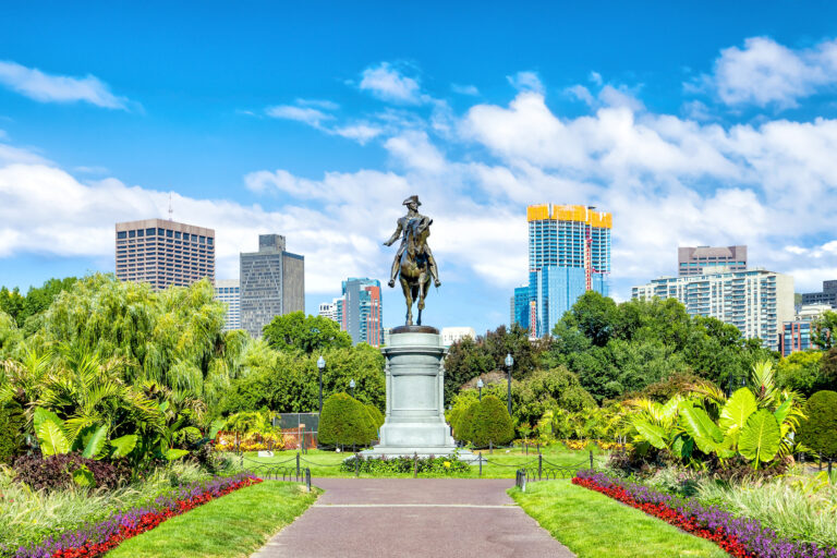 The George Washington statue stands tall amidst the vibrant flora of Boston’s Public Garden, a testament to history surrounded by the city’s modern skyline.