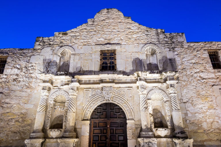The illuminated facade of the historic Alamo stands out against the twilight sky in San Antonio, Texas, a testament to its enduring legacy.
