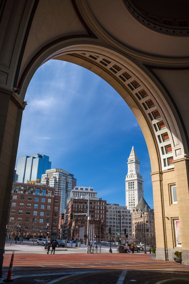 Framed by an elegant archway, the Customs House Clock Tower stands as a historic beacon amidst the modern skyline.