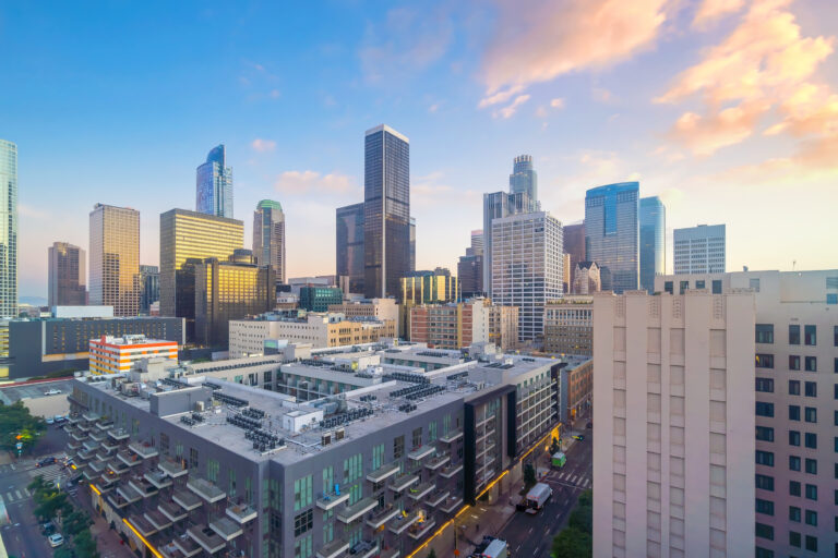 The Los Angeles downtown skyline basks in the warm glow of a stunning sunset, showcasing the city’s architectural beauty.